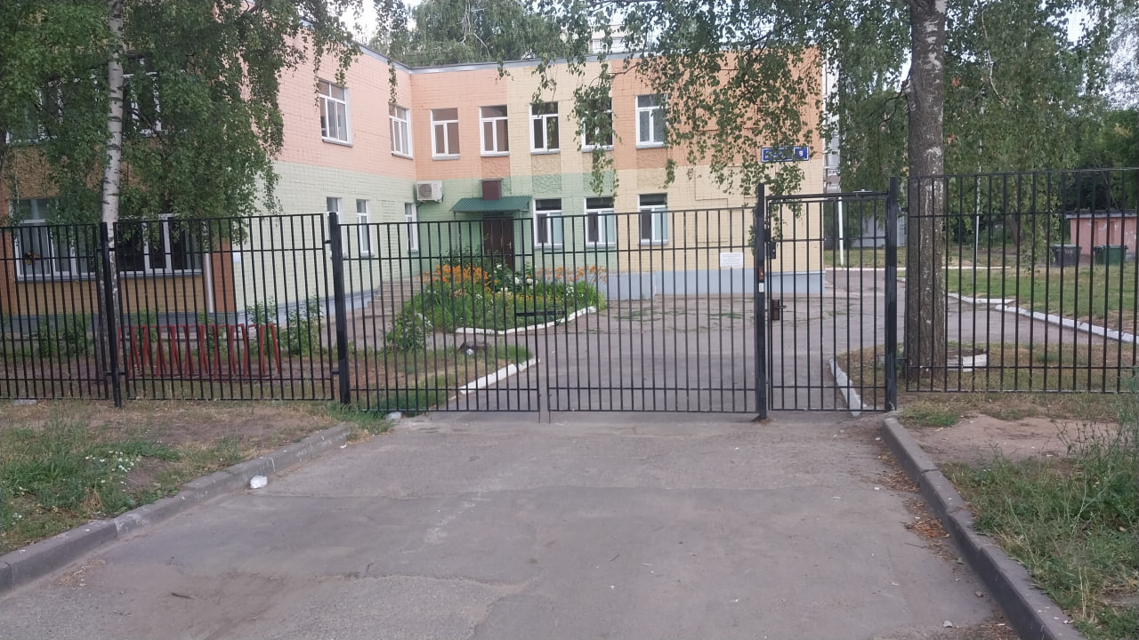 Задняя часть школы огорожена высоким забором.